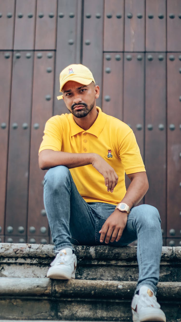 Man In Yellow Polo Shirt And Yellow Cap Sitting