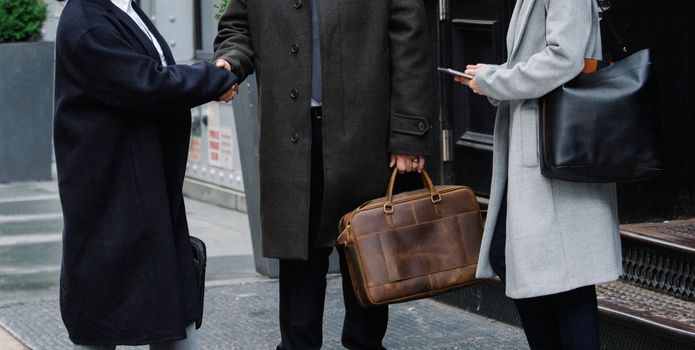 一位穿着优雅外套的匿名时尚商人和一位女商人在街上握手