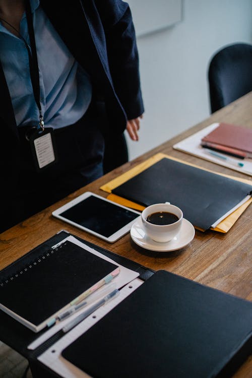 Homme D'affaires Debout Près De La Table Avec Une Tasse De Café Et Des Dossiers