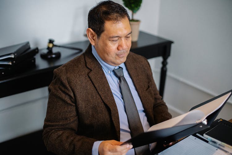 Pensive Asian Lawyer Examining Report In Office