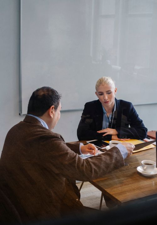 Free Smart colleagues in formal outfit discussing business while sitting at table with cups of coffee in office with whiteboard Stock Photo