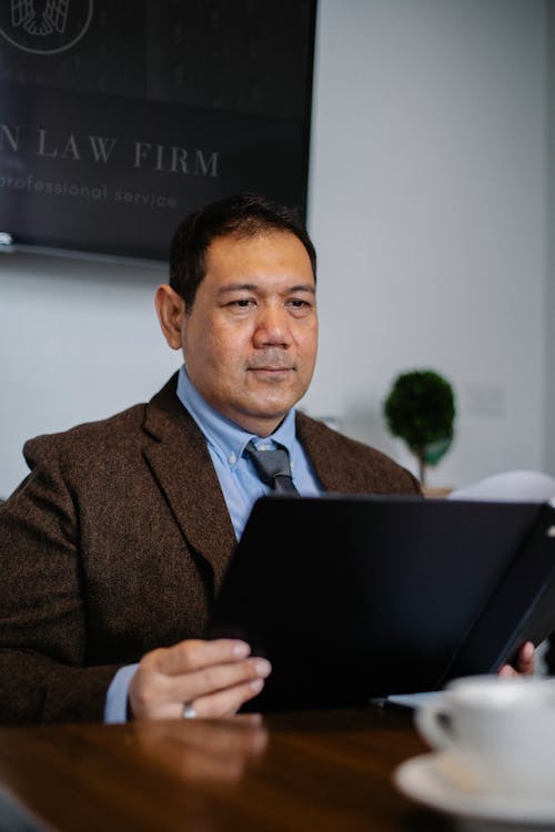 Mature ethnic experienced lawyer in elegant outfit watching important report in folder in office