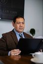 一位穿着优雅的成熟少数族裔资深律师在办公室里翻阅重要报告