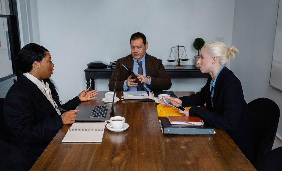 Un grupo diverso de profesionales de negocios reuniéndose en interiores con laptops y documentos.