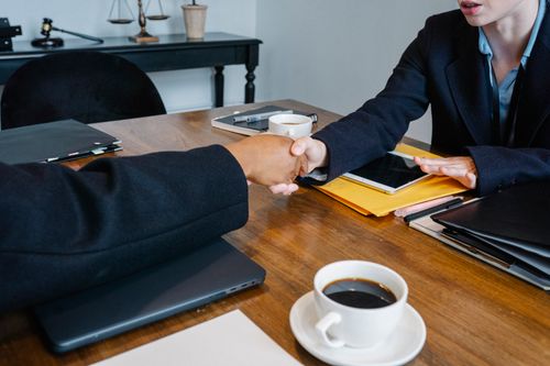Free Crop anonymous multiethnic coworkers in elegant outfit shaking hands at table with tablet and documents in office Stock Photo