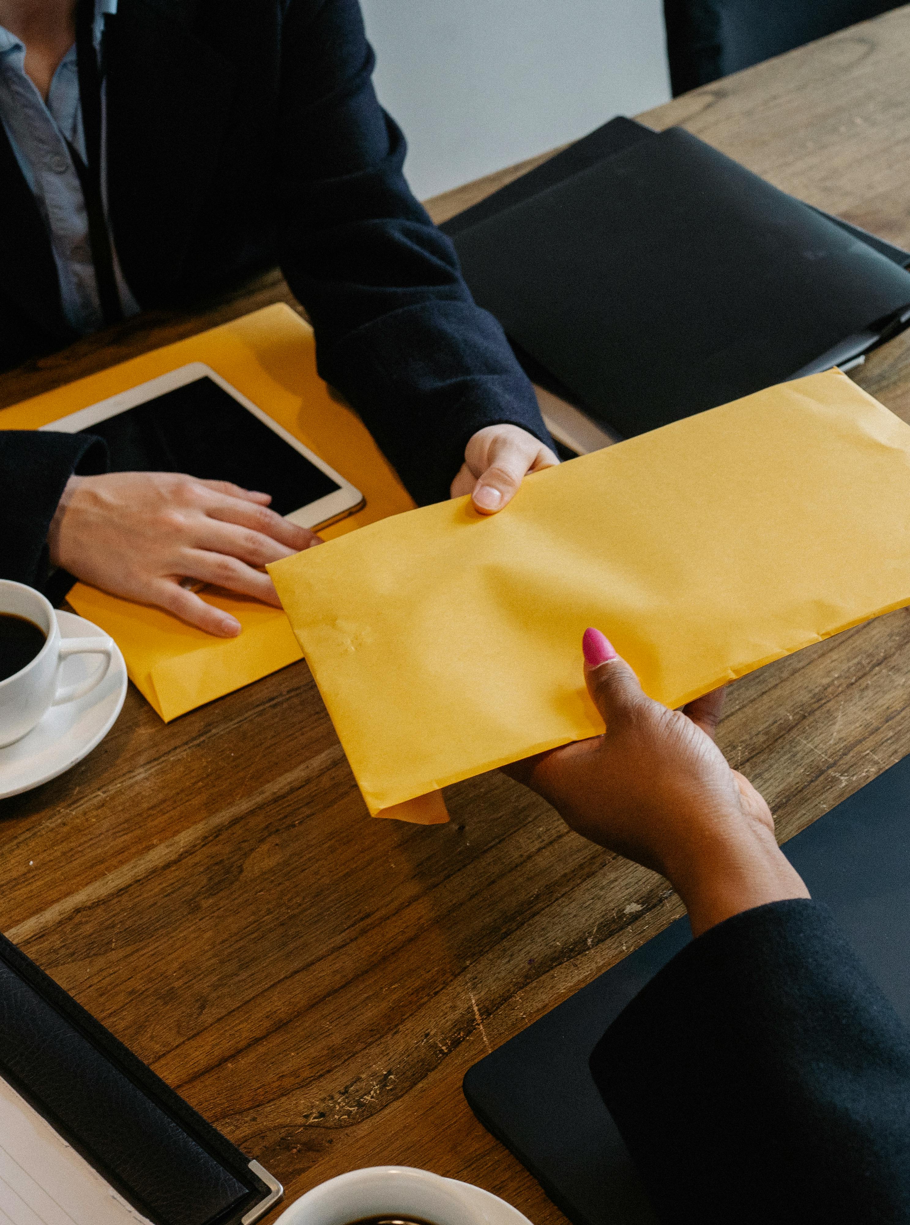 businessman giving bright envelope to black businesswoman