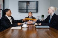 Group of cheerful diverse colleagues discussing court decision at table with notepad and cup