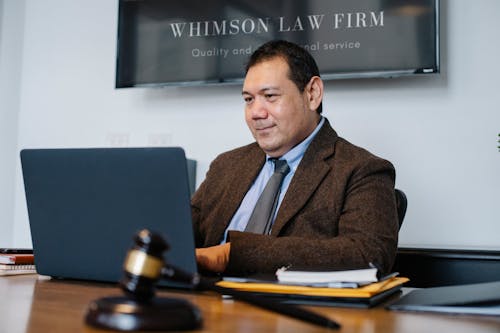 Mature Asian legislator working with laptop at table with gavel