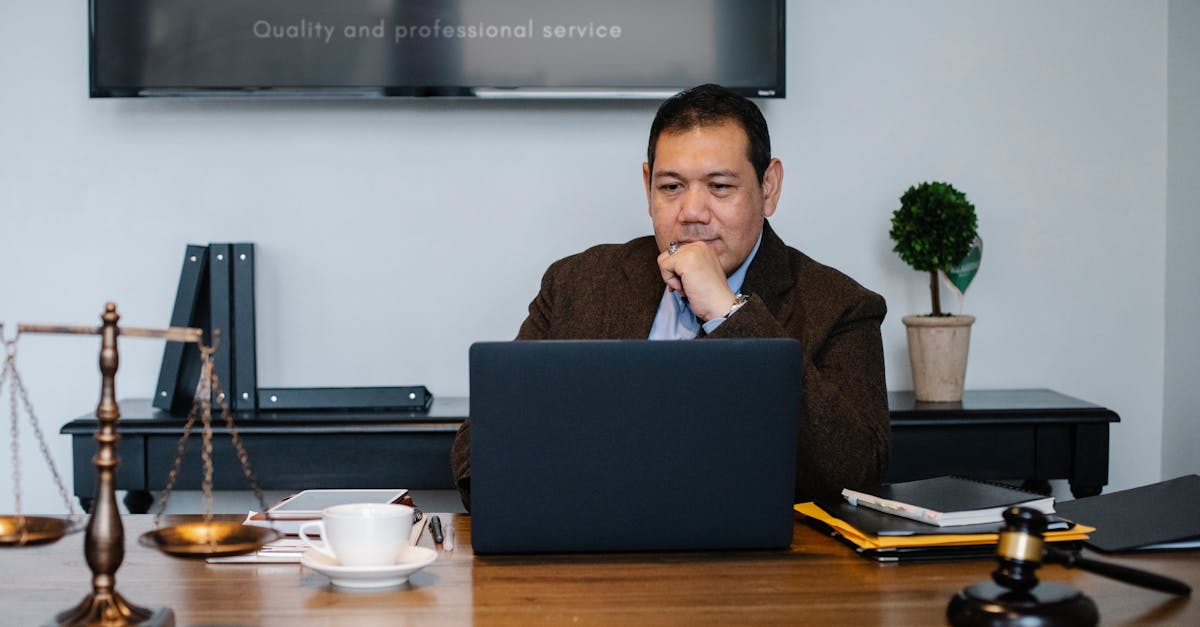 Photo by Sora Shimazaki Serious ethnic mature man in formal outfit working with netbook at table with gavel