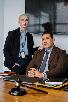独立立法者身着优雅服装，看着桌上的相机与法官锤