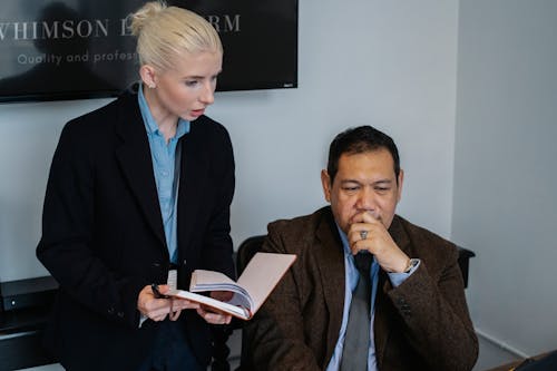 Serious multiracial coworkers in formal clothes gathering together and discussing details of business project while working in office