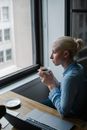 在办公室的咖啡休息时间，一位职业女性若有所思地看着窗外