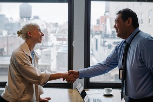 Compañeros Alegres Estrecharme La Mano Mientras Está De Pie En La Mesa