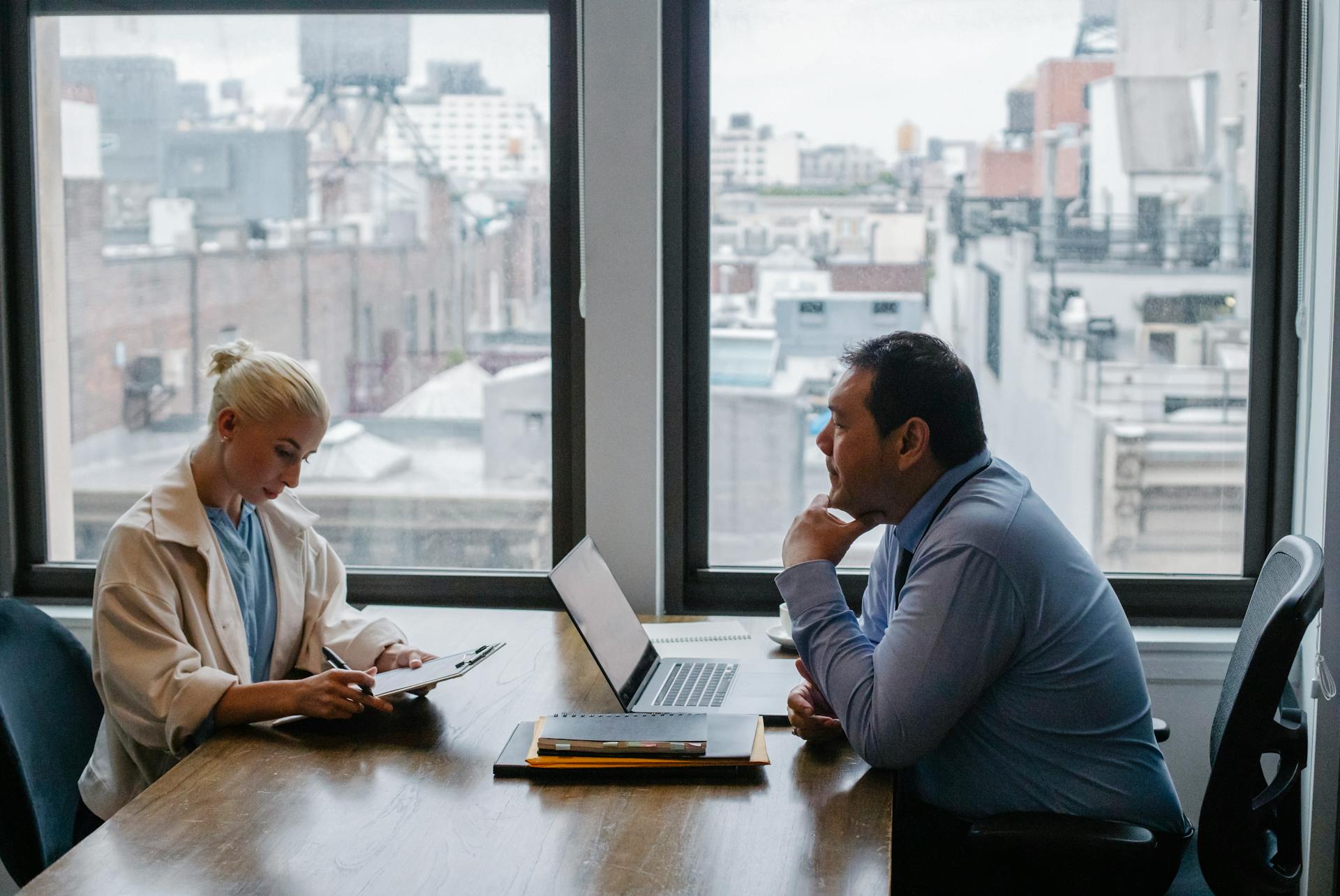 Business meeting between colleagues in a modern office setting with city view.