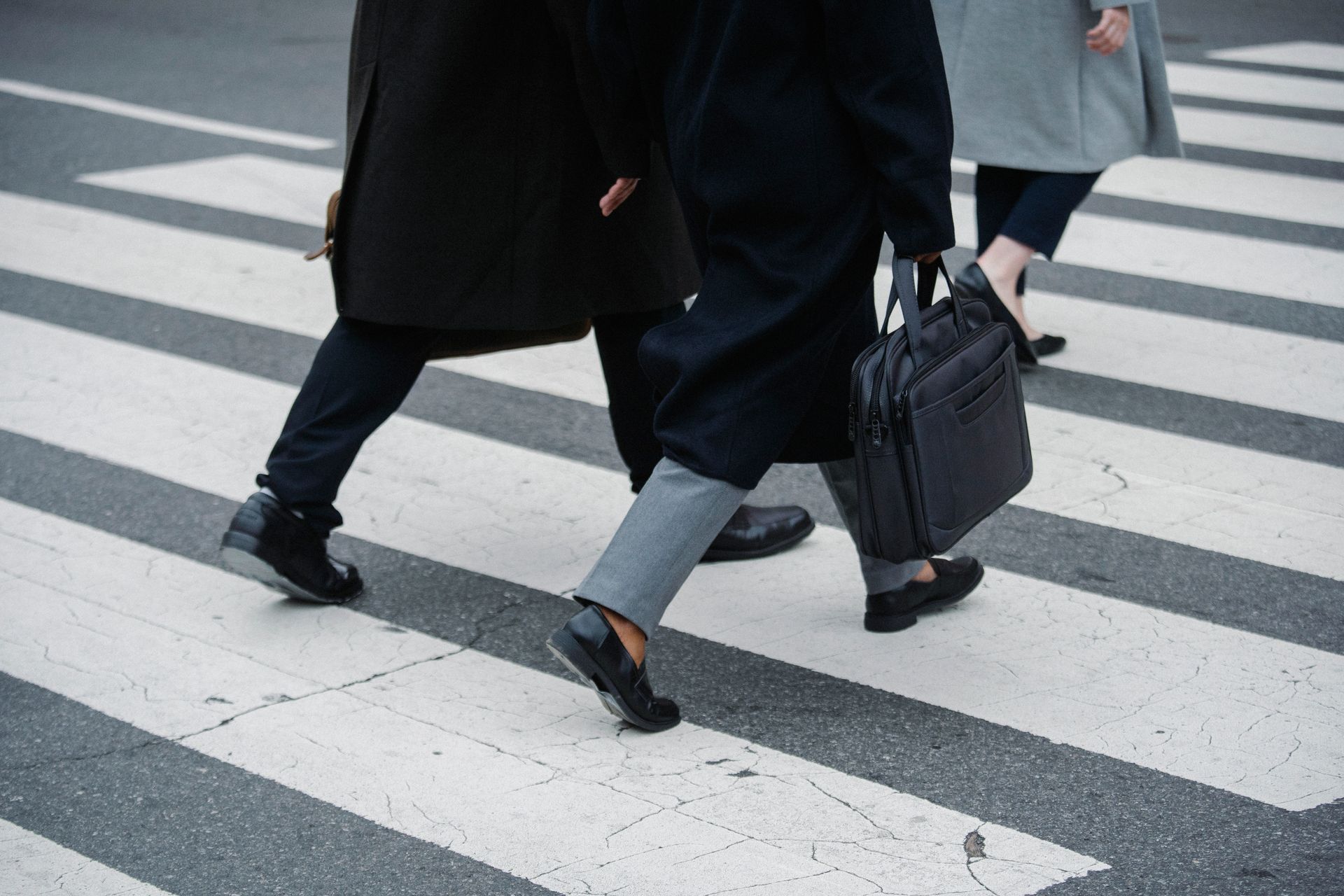 Crop businesspeople strolling on crosswalk in town