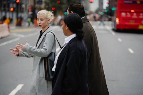 Free Businesswoman talking to unrecognizable multiethnic partners on urban road Stock Photo