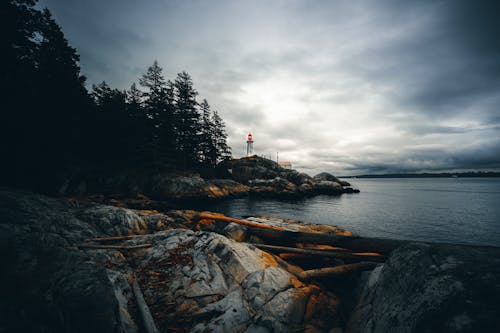 Free Lighthouse in the Rock by the Sea Stock Photo