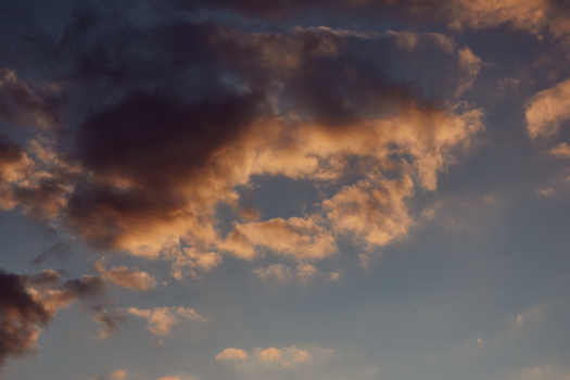 A tranquil evening sky filled with dramatic clouds softly lit by sunset hues.