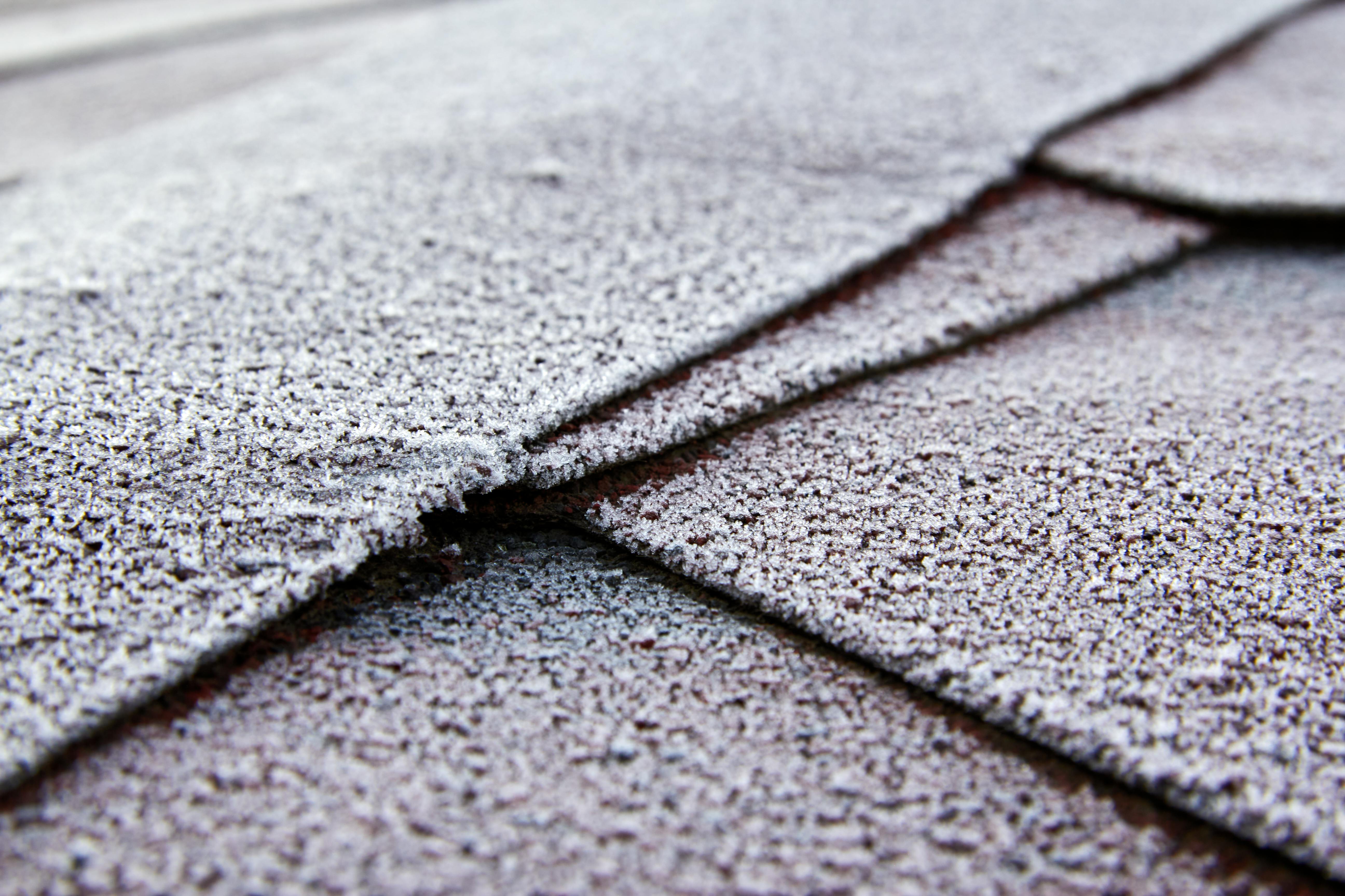 Close-up view of frost-covered roof shingles showcasing texture and cold weather effects.