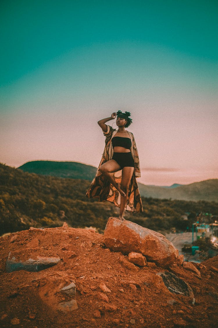 Black Woman Standing On Rock In Hilly Valley