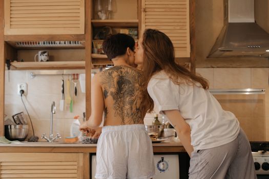 两个女人在舒适的厨房里度过浪漫时刻，凸显了纹身与情感