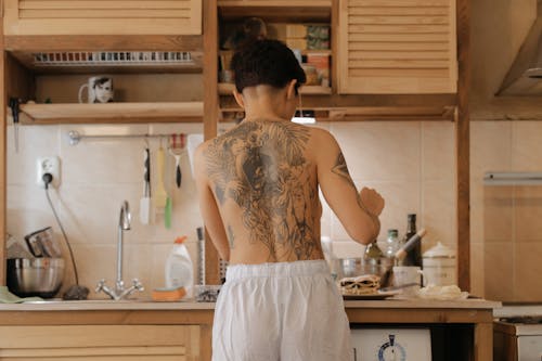 Back View Shot of a Topless Woman Standing Near Kitchen Sink