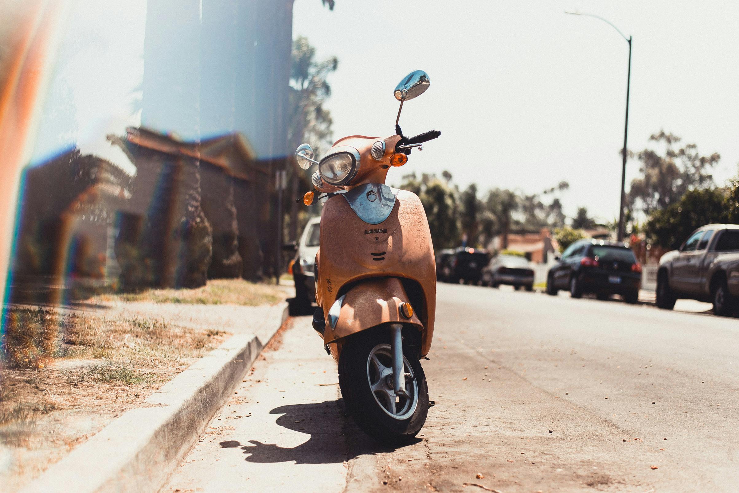 Parked Orange Motor Scooter on Road Near Parked Vehicle · Free Stock Photo