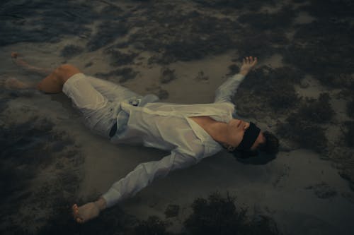 Man in White Dress Shirt Lying on Sand