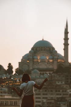 日落时分，一名女子的剪影映衬在伊斯坦布尔令人惊叹的天际线下，其中矗立着一座宏伟的清真寺