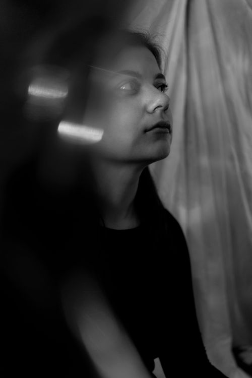 Free Black and white of thoughtful young female sitting near curtain in studio during photo session Stock Photo