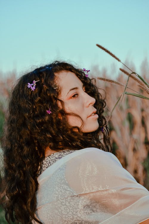 Contemplative woman with reeds in countryside field