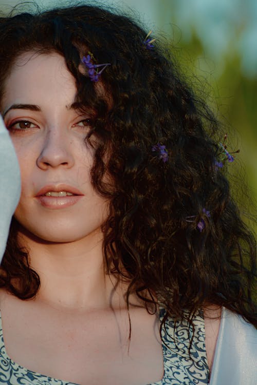 Crop dreamy woman with flowers in curly hair