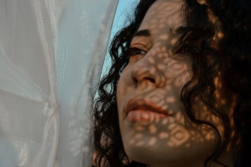 Crop serene woman covering face with veil outside