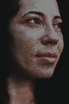 Crop female with dark hair standing with shadows on face and looking away contentedly