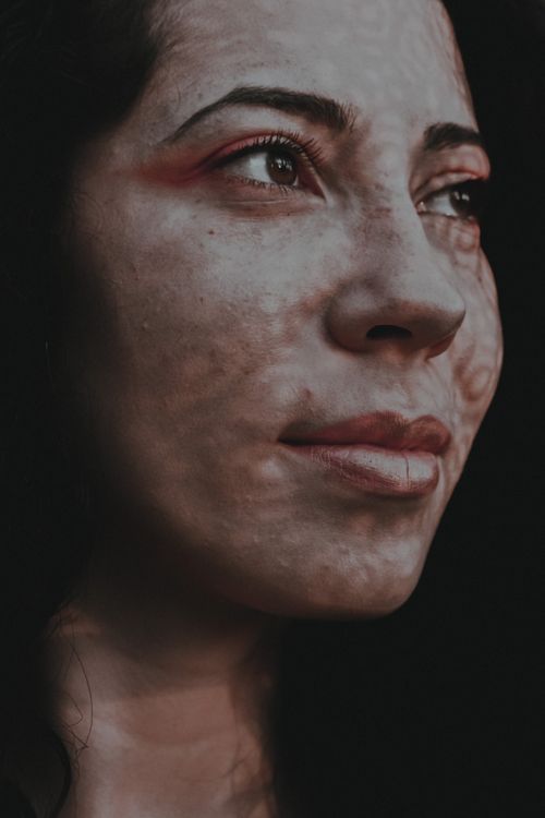 Free Crop female with dark hair standing with shadows on face and looking away contentedly Stock Photo