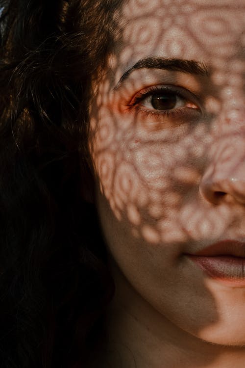 Crop charming woman with shadow on face in sunlight