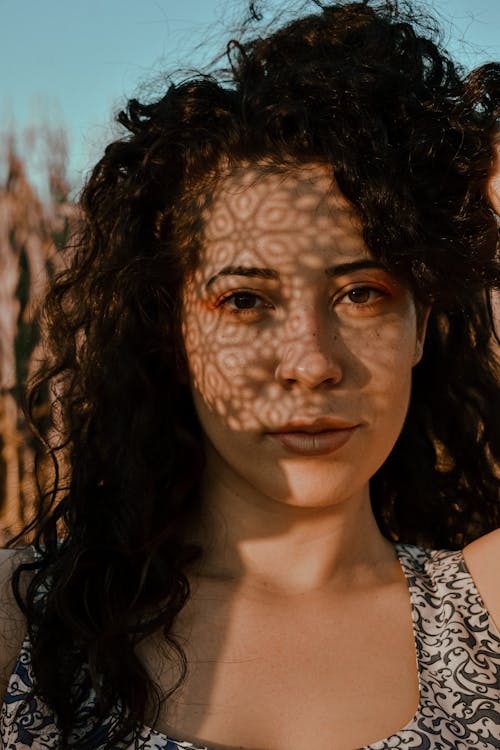 Beautiful woman with shadows on face on sunny meadow