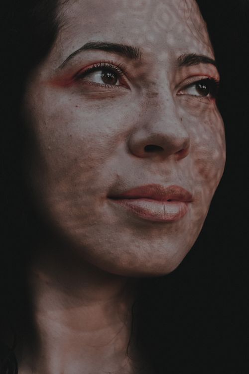 Free Portrait of crop attractive positive female with black hair and shadows on face looking away dreamily Stock Photo