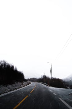 Empty road winding through snowy landscapes in Norwegen, perfect for winter travel themes.