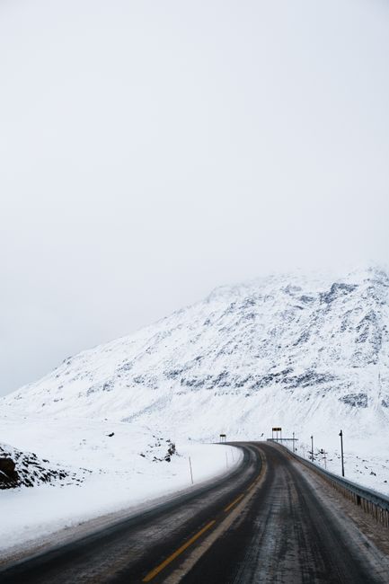 Snow-covered road winding through the winter landscape of Norway.
