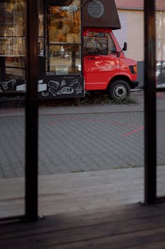 A vibrant red food truck with artistic chalkboard drawings, parked outdoors on a sunny day.