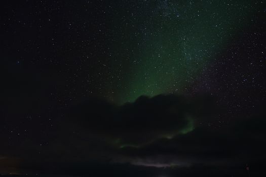挪威上空的迷人星空景色中，隐约可见北极光