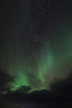 Capture of the Northern Lights illuminating a starry night sky over Norway.