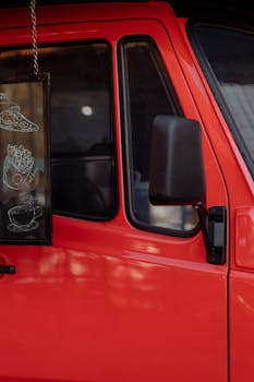 Close-up of a red food truck window with a menu board displaying food items.