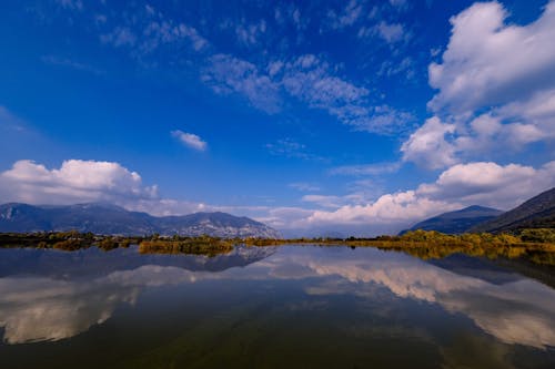 Spectacular landscape of peaceful lake with calm water surface reflecting blue cloudy sky in highlands