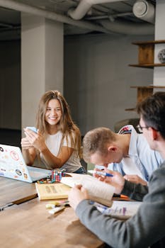 Group of young adults collaborating and enjoying a meeting in a modern workplace setting.