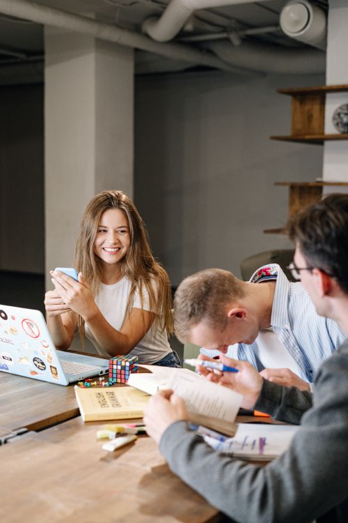 Free Group of young adults collaborating and enjoying a meeting in a modern workplace setting. Stock Photo