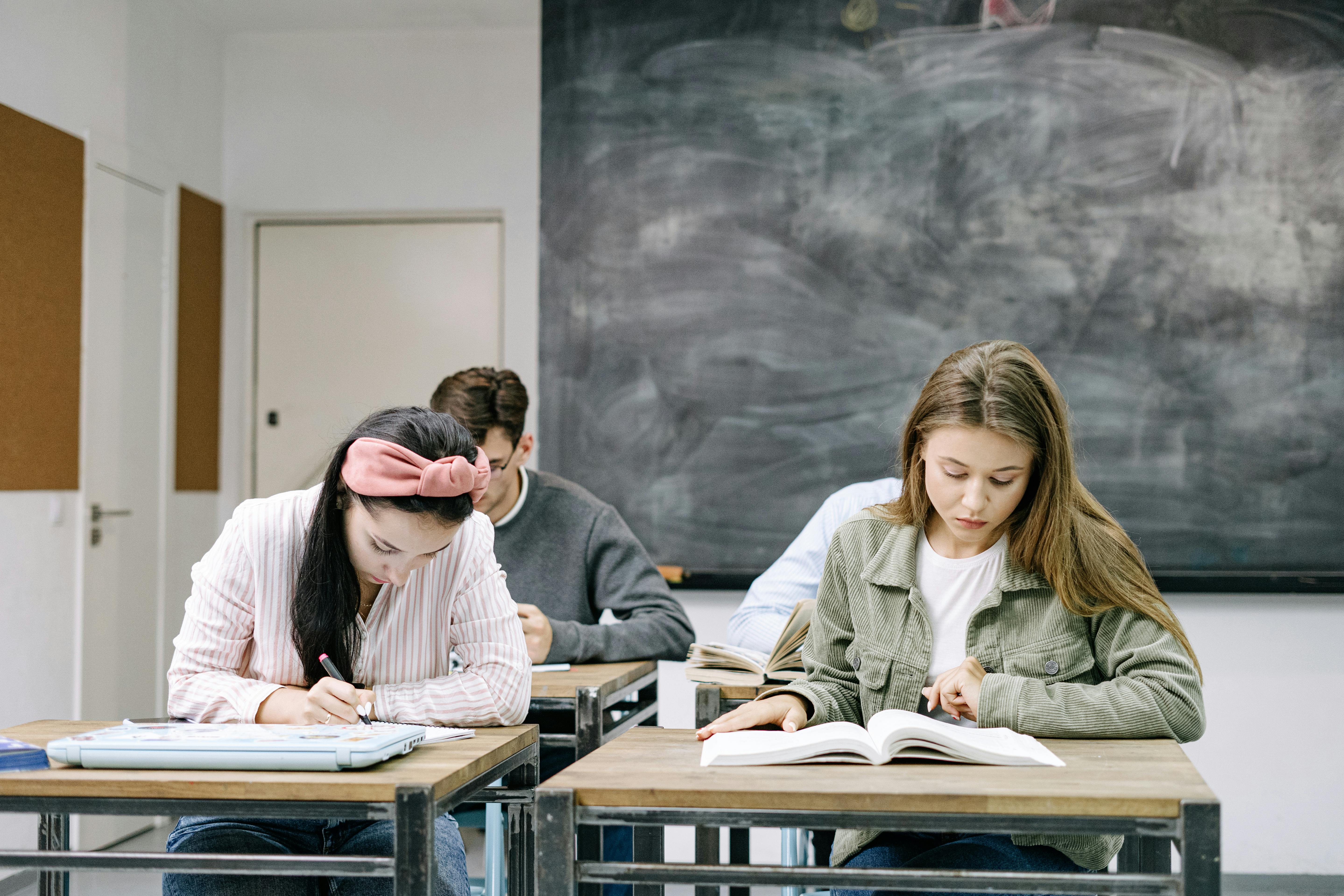 Students seated at desks writing and reading during a classroom exam.
