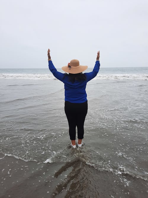 Woman Standing on the Beach Raising Her Hands 