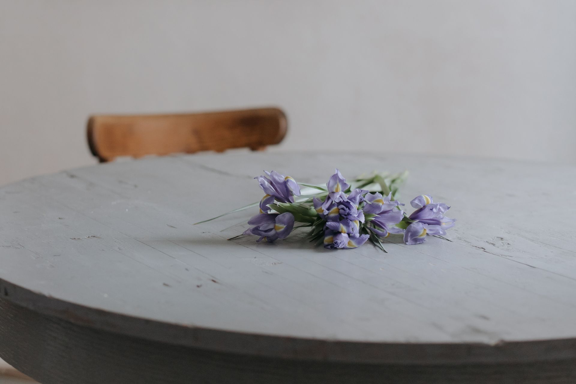 A bunch of lavender iris flowers rest delicately on a rustic wooden table, evoking a tranquil mood.